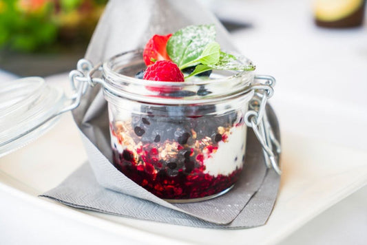 Pote de vidro com iogurte cremoso, geleia de morango e granola
