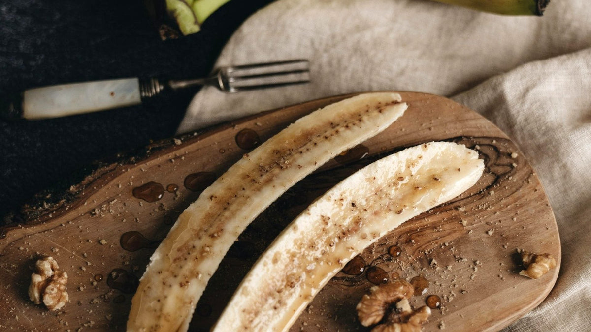 Banana cortada servida em tábua de madeira, alimento naturalmente rico em potássio, associada à saúde muscular.