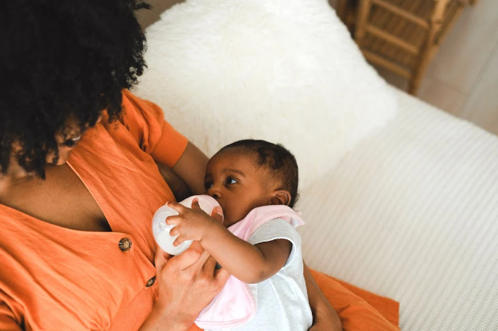 mãe dando mamadeira para bebê