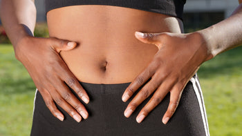 mulher com as duas mão na região da barriga