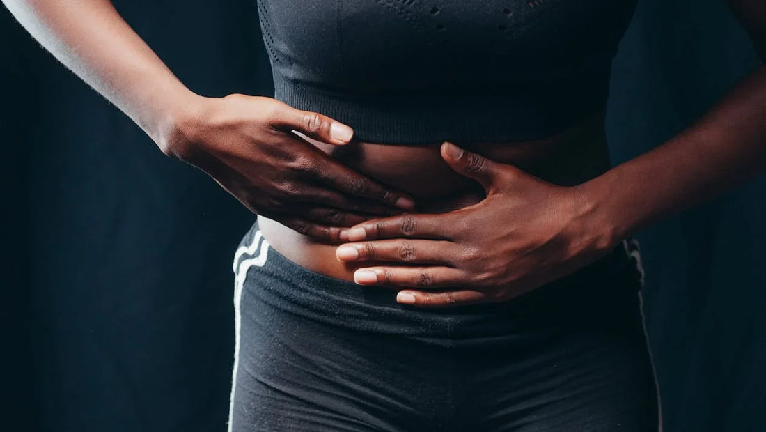 Pessoa com a mão na barriga, destacando ilustração de dor no intestino e desconforto abdominal